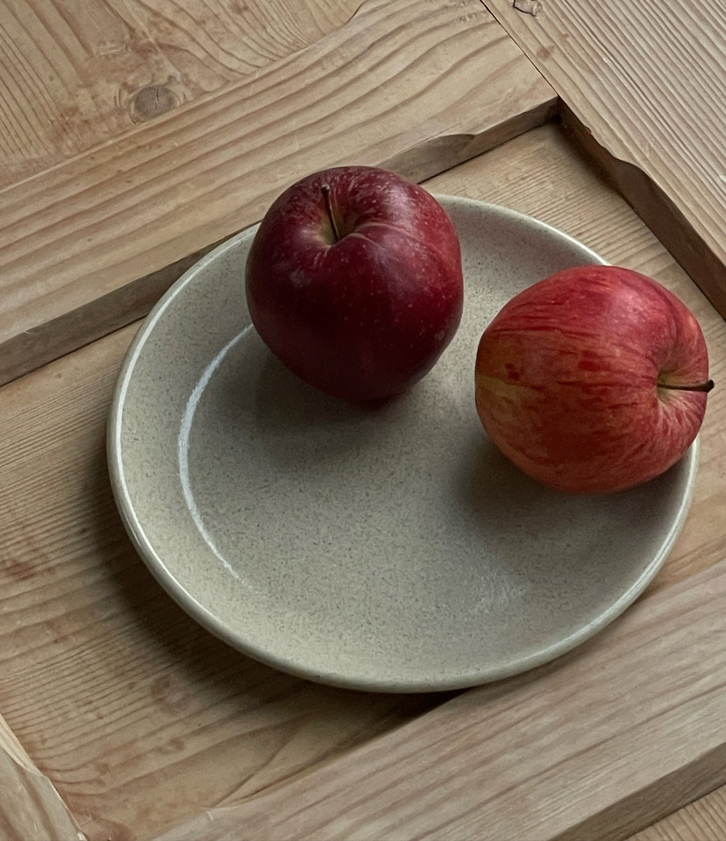 Kleiner Keramik Teller Kollektion Viana auf Holzbrett mit zwei roten Äpfeln drauf. 